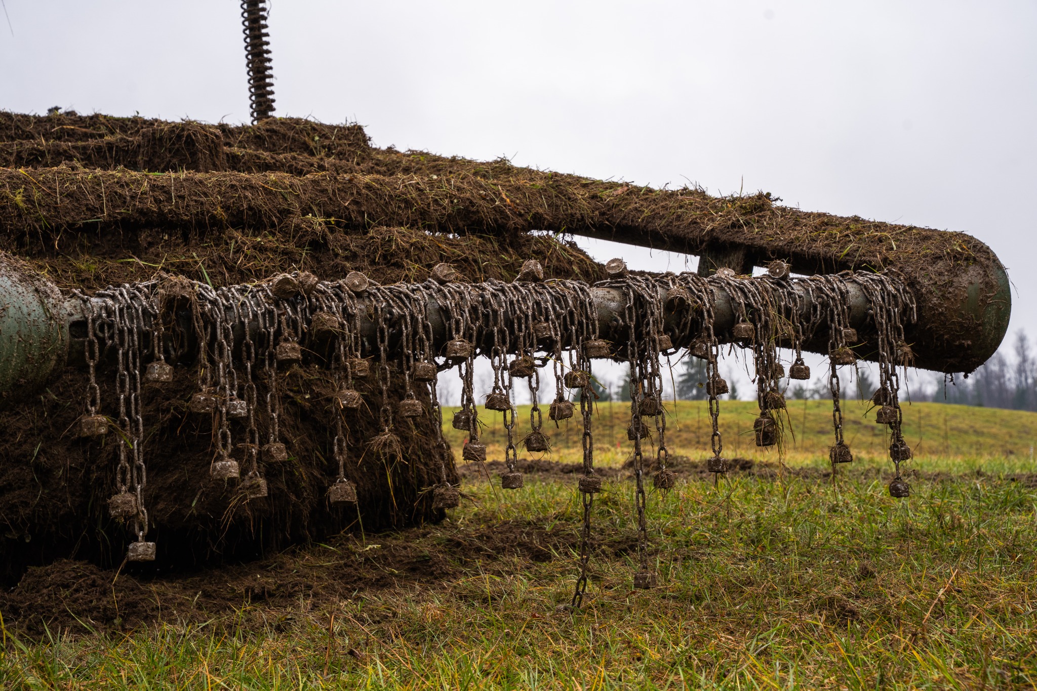 Close-up of the DeMiner flail chains covered in soil during field operation